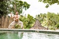 Handsome man in costume practice qigong exercises outdoors in summer terrace near the pool. Healing and spiritual Wellness, Bali,