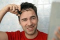 Self-care in the conditions of global quarantine and closed hairdressers and beauty salons. Handsome man cutting his own hair with Royalty Free Stock Photo