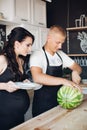 Handsome man cutting watermelon and sharing it with wife.