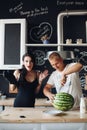 Handsome man cutting watermelon and sharing it with wife.