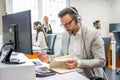 Handsome man dispatcher taking notes while talking with customer in office Royalty Free Stock Photo