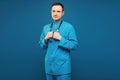 Handsome man doctor in blue medical uniform posing with stethoscope on the blue background. Concept of healthcare and Royalty Free Stock Photo