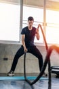 Handsome man doing battle ropes exercise workout it best cardio at fitness gym Royalty Free Stock Photo