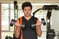 Handsome man doing biceps lifting with dumbbell on bench in a gym Royalty Free Stock Photo