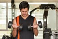 Handsome man doing biceps lifting with dumbbell on bench in a gym Royalty Free Stock Photo