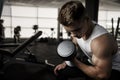 Handsome man doing biceps lifting with dumbbell on bench in a gym Royalty Free Stock Photo