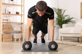 Handsome man doing plank exercise with dumbbells on floor at home Royalty Free Stock Photo