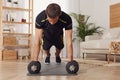 Handsome man doing plank exercise with dumbbells on floor at home Royalty Free Stock Photo