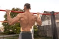 Handsome man doing pull ups outdoors, seen from behind, close up Royalty Free Stock Photo