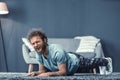 Handsome man doing push up or abs core plank exercise at home laughing looking at camera. Funny curly hair man with a Royalty Free Stock Photo