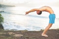 Handsome man doing yoga at cliff with blue sea background Royalty Free Stock Photo