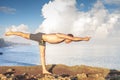 Handsome man doing yoga at cliff with blue sea background Royalty Free Stock Photo