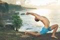 Handsome man doing yoga at cliff with blue sea background Royalty Free Stock Photo