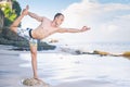 Handsome man doing yoga at cliff with blue sea background Royalty Free Stock Photo