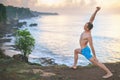 Handsome man doing yoga at cliff with blue sea background Royalty Free Stock Photo