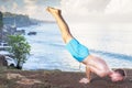 Handsome man doing yoga at cliff with blue sea background Royalty Free Stock Photo