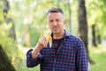 Handsome man eating banana outdoor. Outdoor autumnal male portrait. Attractive confident middle-aged man