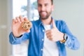 Handsome man eating chocolate chips cookies happy with big smile doing ok sign, thumb up with fingers, excellent sign Royalty Free Stock Photo