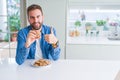 Handsome man eating chocolate chips cookies happy with big smile doing ok sign, thumb up with fingers, excellent sign Royalty Free Stock Photo