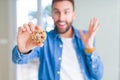 Handsome man eating chocolate chips cookies very happy and excited, winner expression celebrating victory screaming with big smile Royalty Free Stock Photo