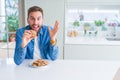 Handsome man eating chocolate chips cookies very happy and excited, winner expression celebrating victory screaming with big smile Royalty Free Stock Photo