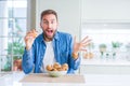 Handsome man eating chocolate chips muffin very happy and excited, winner expression celebrating victory screaming with big smile Royalty Free Stock Photo