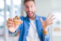 Handsome man eating chocolate chips muffin very happy and excited, winner expression celebrating victory screaming with big smile Royalty Free Stock Photo