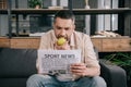 Man eating fresh apple while reading sport news newspaper at home