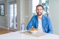 Handsome man eating pasta with meatballs and tomato sauce at home with a happy and cool smile on face Royalty Free Stock Photo