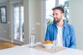 Handsome man eating pasta with meatballs and tomato sauce at home looking away to side with smile on face, natural expression Royalty Free Stock Photo