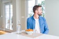 Handsome man eating pasta with meatballs and tomato sauce at home looking to side, relax profile pose with natural face with Royalty Free Stock Photo