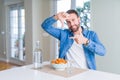 Handsome man eating pasta with meatballs and tomato sauce at home smiling making frame with hands and fingers with happy face Royalty Free Stock Photo