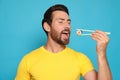 Handsome man eating sushi roll with chopsticks on light blue background Royalty Free Stock Photo