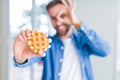 Handsome man eating sweet Belgian pancakes with happy face smiling doing ok sign with hand on eye looking through fingers Royalty Free Stock Photo