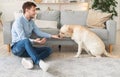 Handsome man feeding his dog in the living room Royalty Free Stock Photo