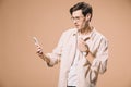 Handsome man in glasses looking at smartphone while listening music in earphones  isolated Royalty Free Stock Photo