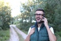 Handsome man with glasses phoning in the park. Beautiful man with hand on the face Royalty Free Stock Photo