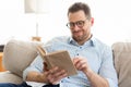 Handsome man in glasses reading a book at home Royalty Free Stock Photo