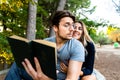 Handsome man with glasses seduces young woman reading him a book Royalty Free Stock Photo