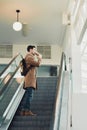 Handsome man going up on escalator and drinking Royalty Free Stock Photo