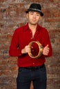 Handsome man in hat poses with tambourine in