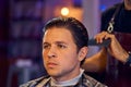 Handsome man is while having his hair cut by hairdresser at the barbershop, close up portrait. Work in the Barber shop