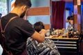 Handsome man is while having his hair cut by hairdresser at the barbershop, close up portrait. Work in the Barber shop