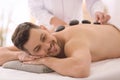 Handsome man having stone massage in spa salon