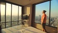 Handsome man in his room in luxury hotel is looking beautiful sunrise. Nice guy lives or freelancing works in hotel. Man Royalty Free Stock Photo