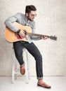 Handsome man holding an acoustic guitar against grunge wall Royalty Free Stock Photo