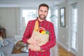 Handsome man holding groceries bag with a happy face standing and smiling with a confident smile showing teeth Royalty Free Stock Photo