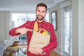 Handsome man holding groceries bag very happy pointing with hand and finger Royalty Free Stock Photo