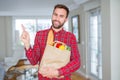Handsome man holding groceries bag very happy pointing with hand and finger to the side Royalty Free Stock Photo