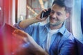 Handsome man holding newspaper while talking on mobile phone Royalty Free Stock Photo